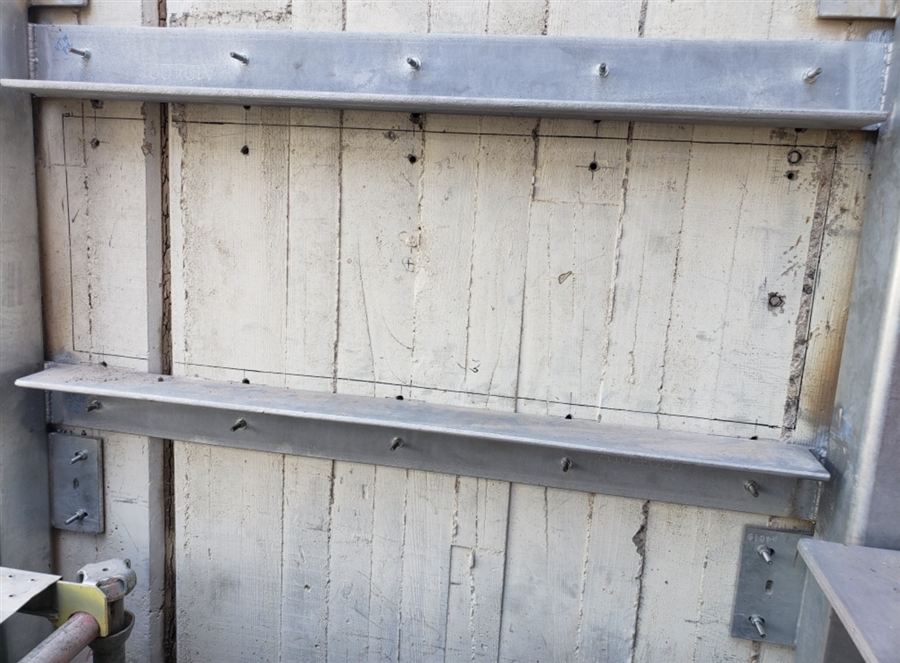 Concrete wall with the opening laid out in pencil lines and pilot marks, steel bracing in place
